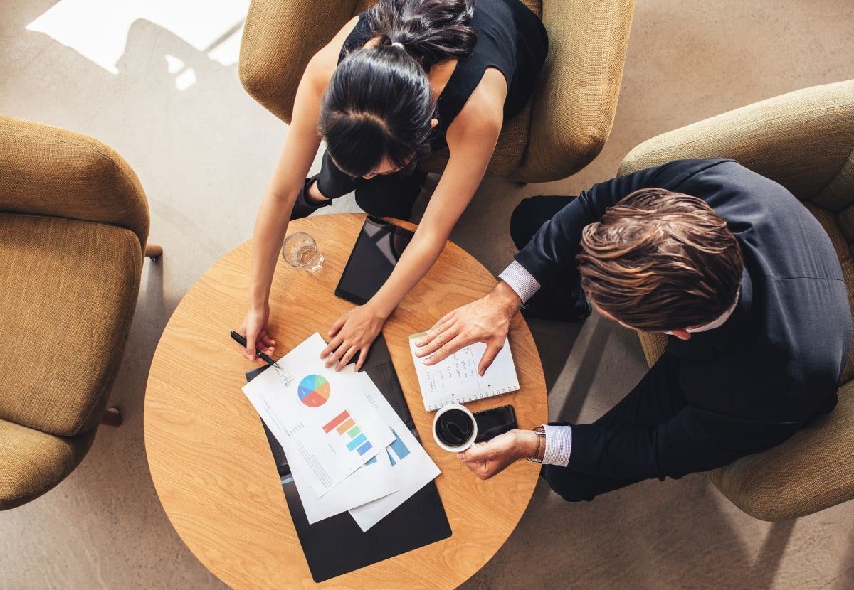 Executives in a corporate boardroom meeting reviewing charts and reports