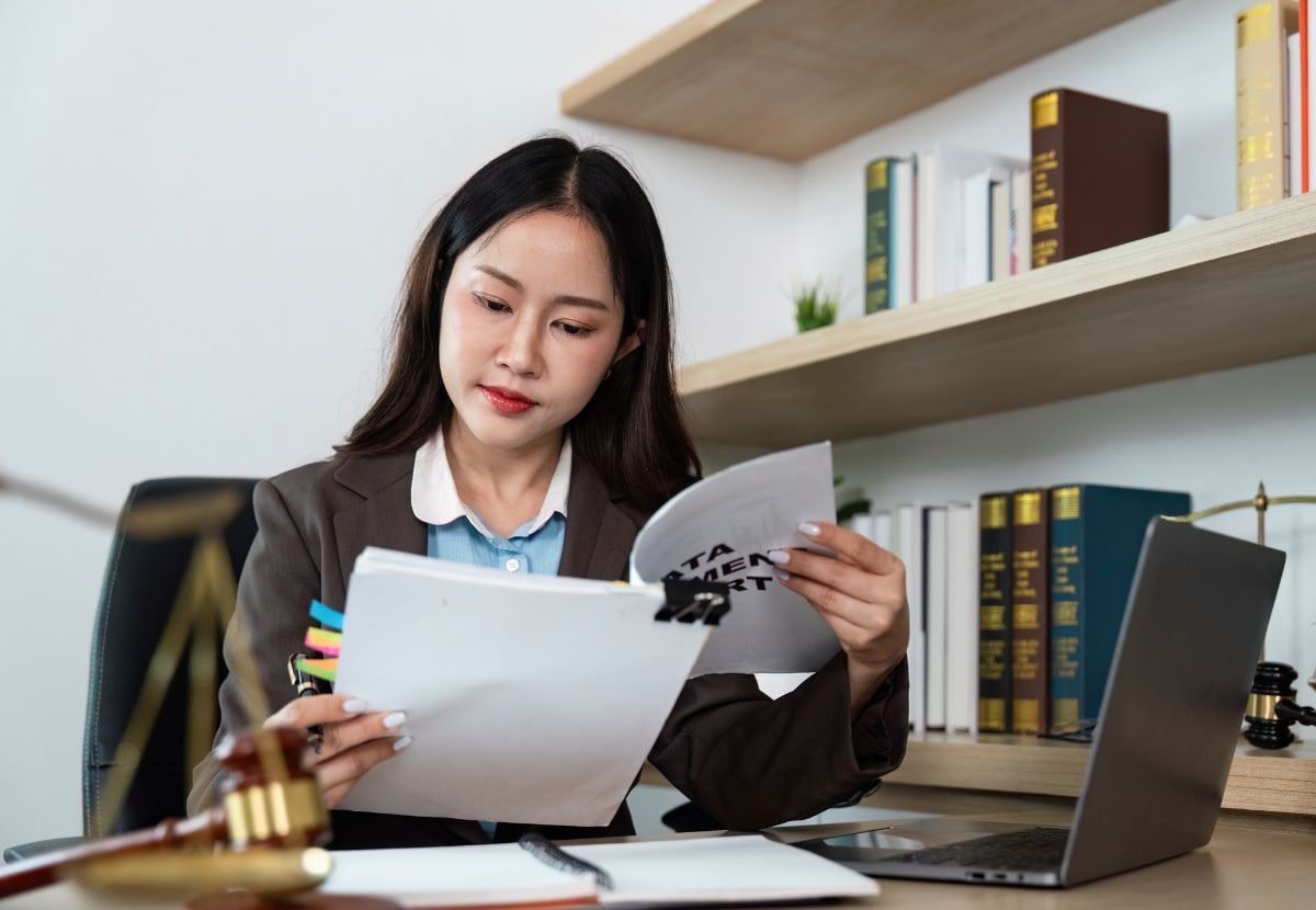 Lawyer reviewing legal documents at her desk with law books and a gavel