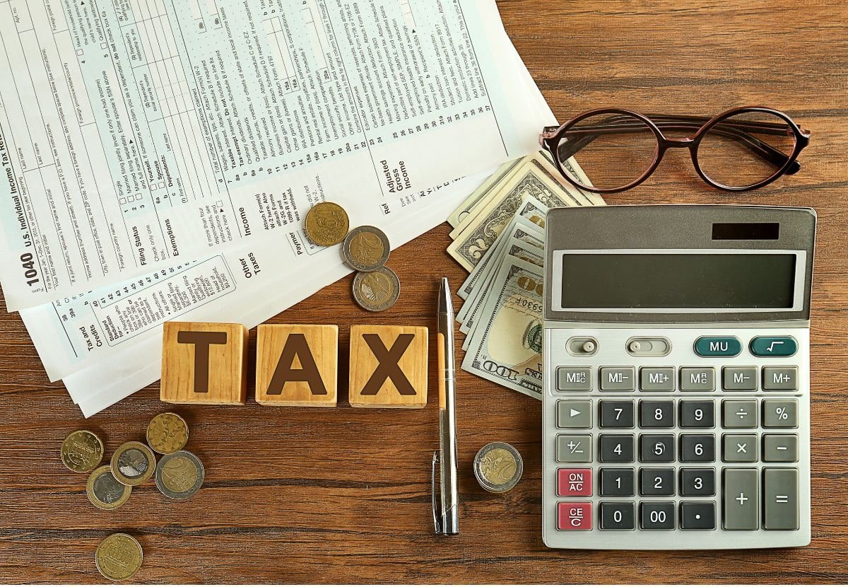 Tax wooden blocks, calculator, cash, and income tax form on a desk